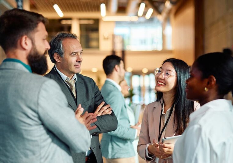 Group of multi-ethnic businesspeople engaging in networking and discussing ideas during a corporate event or convention, fostering collaboration and building professional relationships